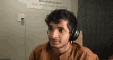 a young man wearing headphones is sitting in front of a sign that says `` your mind is our business ''