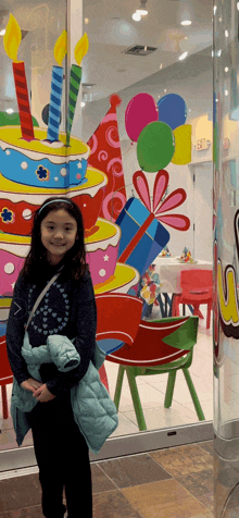 a little girl is standing in front of a birthday cake display