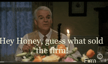 a man is sitting at a table with a candle and flowers and says hey honey guess what sold the firm