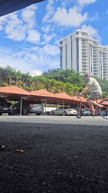 a man is riding a bike in a parking lot with a building in the background