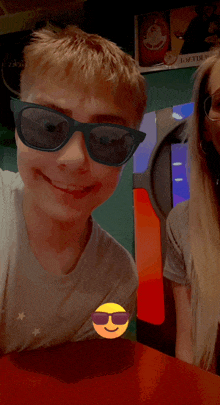 a boy wearing sunglasses is smiling next to a woman wearing glasses