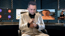 a man in a suit adjusts his cufflinks in front of a screen that says bordeaux on it