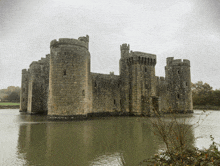 a large stone castle is surrounded by water on a cloudy day