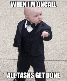 a baby wearing a tuxedo and bow tie points to the right