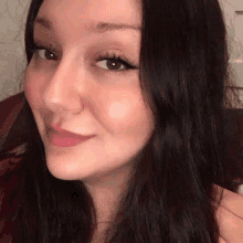 a close up of a woman 's face with long dark hair and a smile on her face .