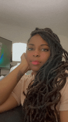 a woman with dreadlocks looks at the camera with her hand on her chin