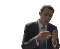 a man in a suit and tie is holding his hands together and looking at his phone .