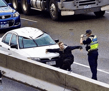 a police officer is taking a picture of a man sitting next to a car