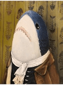 a stuffed shark wearing a jacket and scarf is standing in front of a wall .