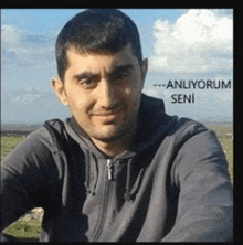 a man wearing a grey hoodie with the words anliyorum seni written on the bottom