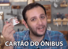 a man in a plaid shirt is holding up a card that says " cartao do onibus "