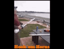 a man is holding a fishing rod in front of a picnic table with the words hook em horns above him