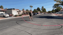 a woman is playing with a hula hoop in a circle on a street that says " awesome " on the bottom