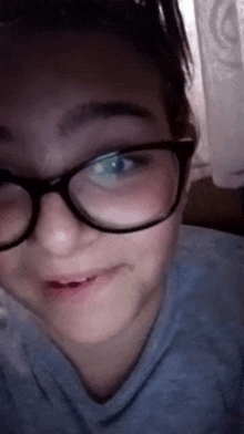 a girl wearing glasses and a blue shirt is making a funny face