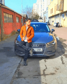 a man stands next to an audi with a license plate that says kj 6984