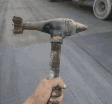 a person is holding a rusty hammer with a bomb on it .