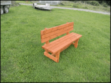 a wooden bench is sitting in the middle of a grassy field