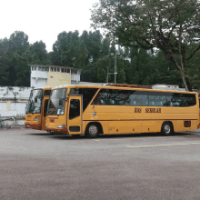 a yellow bus that says bas sekolah is parked next to another bus