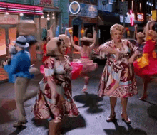 a group of women are dancing on a street in front of a sign that says ' ice cream '