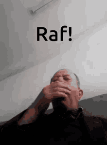 a man covering his mouth in front of a sign that says raf on it