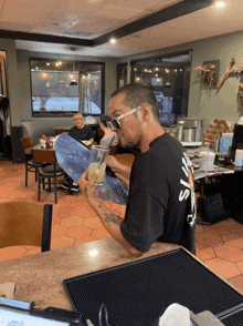 a man in a black shirt with the word jesus on the back is pouring a drink