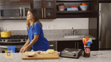 a woman in a blue shirt is preparing food in a kitchen with a jar of salsa on the counter