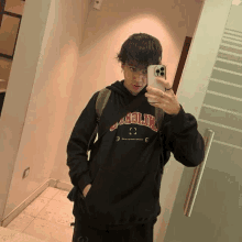 a young man is taking a picture of himself in a mirror while wearing a hoodie that says ' california '