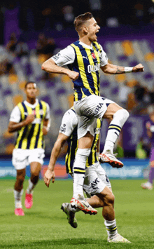 a soccer player wearing a yellow and blue uniform with the word oto on it jumps in the air