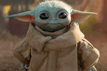 a baby yoda doll with a scarf around his neck