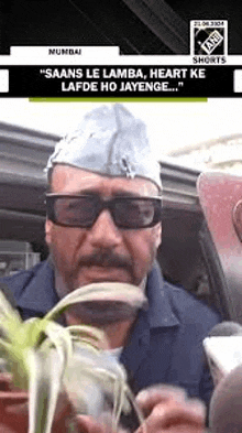 a man wearing sunglasses and a hat is holding a plant in his hands .