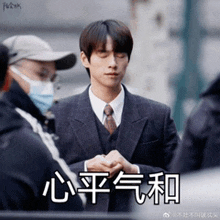 a man in a suit and tie is standing in front of a group of people with chinese writing on them .