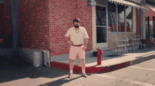 a man stands on the sidewalk in front of a brick building with a sign that says ' ice cream '