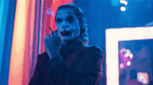 the joker is smoking a cigarette in a dark room in a movie .