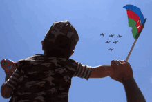 a child is holding a flag in front of a blue sky with planes flying in the background