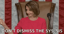 a woman in a red shirt is sitting in a chair in front of a microphone and a flag .