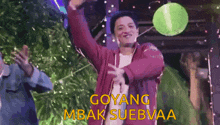 a man in a red jacket is dancing with his arms in the air and the words goyang mbak suebvaa