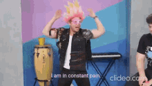 a man in a pink wig and goggles is dancing and says i am in constant pain