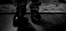 a black and white photo of a person 's feet dancing on a wooden floor .