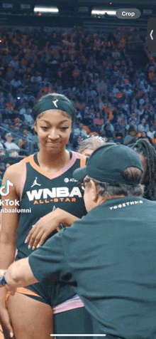 a woman in a wnba all star uniform is being hugged by a man