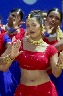 a woman in a red crop top is dancing in front of a crowd