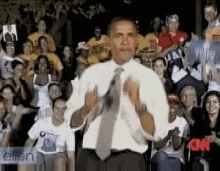 a man in a white shirt and tie stands in front of a crowd with cnn written on the bottom right corner