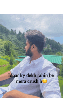 a man in a white shirt is sitting in front of a green roof with the words idhar ky dekh rahin be mera crush