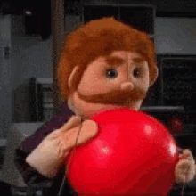 a puppet with a beard and mustache is holding a red ball .