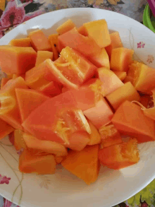 sliced papaya on a white plate with flowers on it