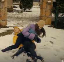 a man and woman are playing in the snow and the woman is wearing a purple jacket