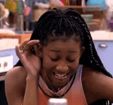 a woman with braids is smiling while sitting at a table .