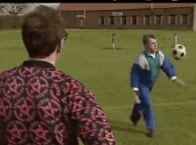 two men are playing soccer on a field and one of them is kicking a soccer ball .