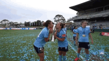 two female soccer players kissing a trophy on a field with a sign that says ' congratulations ' on it