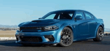 a blue dodge charger srt hellcat is parked on the side of a road .