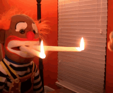 a clown puppet holds a lit candle in his mouth